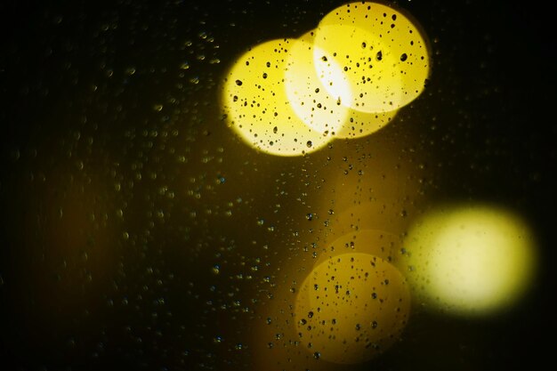 Zdjęcie zbliżenie rozmytych świateł widzianych przez mokre okno w porze deszczowej