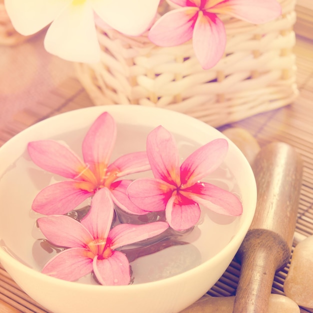 Zbliżenie różowych kwiatów frangipani w misce z wodą na stole w spa