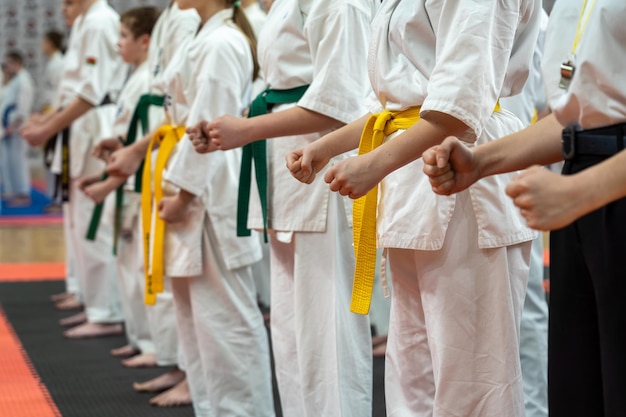Zbliżenie rzędu dzieci w białych kimono karate z zaciśniętymi pięściami