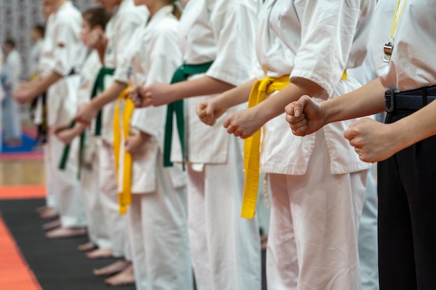 Zbliżenie rzędu dzieci w białych kimono karate z zaciśniętymi pięściami