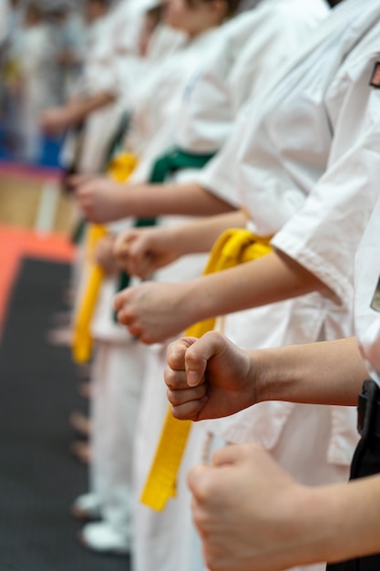 Zbliżenie rzędu dzieci w białych kimono karate z zaciśniętymi pięściami