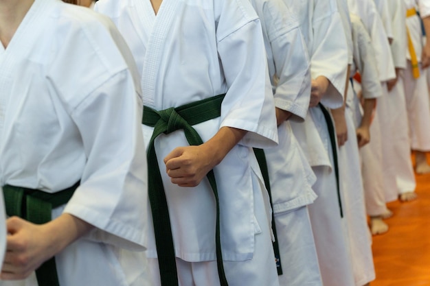 Zbliżenie rzędu dzieci w białych kimono karate z zaciśniętymi pięściami