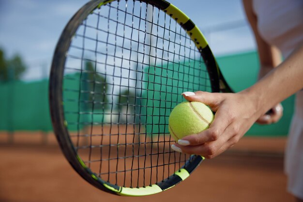 Zbliżenie selektywny nacisk na piłkę i rakietę tenisową w kobiecej dłoni. Prywatny klub sportowy do treningu i profesjonalny sprzęt do koncepcji gry