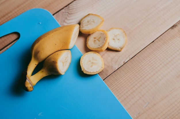 Zdjęcie zbliżenie skórkowanego na plasterki banana na drewnianym tle stołu