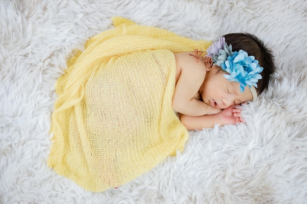 Zbliżenie słodkiego noworodka w opasce kwiatowej na wełnianych dywanach, koncepcja mody