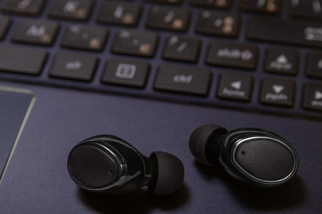 Zbliżenie słuchawek bezprzewodowych leżących na klawiaturze laptopa