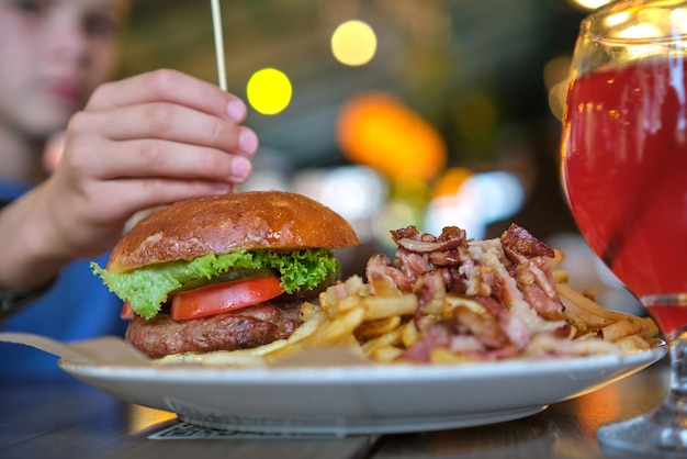 Zbliżenie smaczny hamburger i frytki z mięsem na talerzu w restauracji.