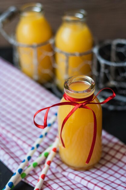 Zdjęcie zbliżenie soku pomarańczowego w butelce na stole