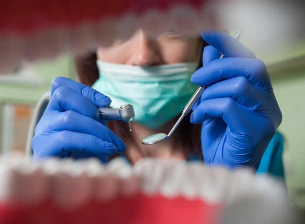 Zbliżenie sprzętu stomatologicznego. Dentysta trzyma bur i lusterko dentystyczne