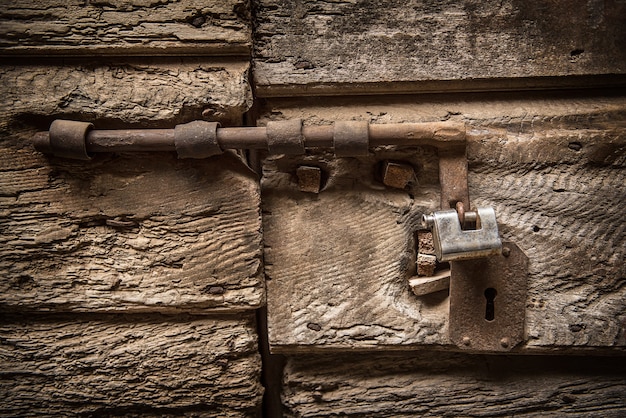 Zbliżenie starego żelaznego zamka na drewniane antyczne drzwi, tło rustykalne grunge