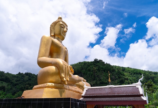 Zbliżenie starożytny złoty duży posąg Buddy obrazu (Wat Phra Chao Ton Luang) w świątyni Wat Na Ku Ha lub Nakuha z pochmurnego nieba, cel podróży w Phrae, Tajlandia