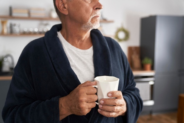 Zbliżenie starszego mężczyzny trzymającego filiżankę kawy w domu
