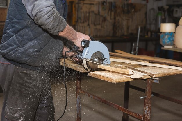 Zbliżenie stolarza pracująca piła tarczowa Stolarz pił drewniane klocki i drewniane łupki