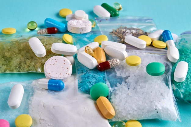 Zbliżenie stos różnych kolorowych tabletek z witaminami medycyny kapsułek i tabletek na niebieskim tle