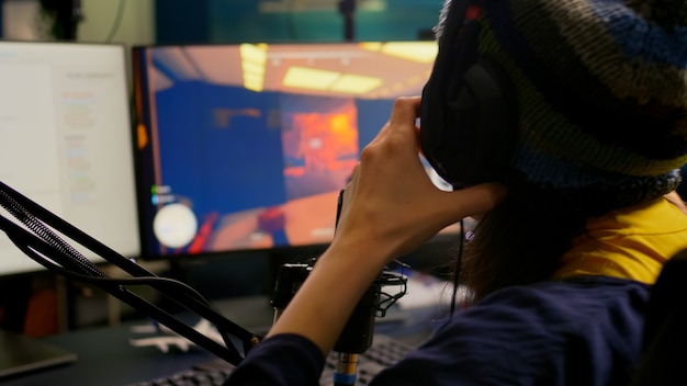 Zbliżenie streamera noszącego profesjonalne słuchawki do gier i grającego w gry wideo FPS
