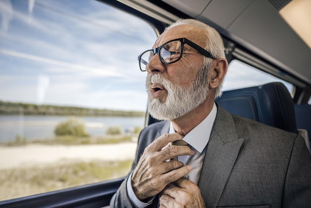 Zbliżenie stresującego się starszego biznesmena podróżującego pociągiem po zawale serca