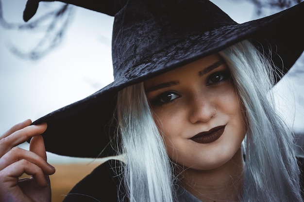Zdjęcie zbliżenie strzał młodej uśmiechniętej dziewczyny rasy kaukaskiej w kostiumie czarownicy i makijażu na halloween