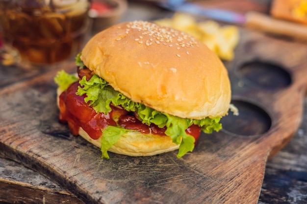 Zbliżenie świeżego burgera z frytkami na drewnianym stole z miskami sosu pomidorowego. żywność stylu życia.