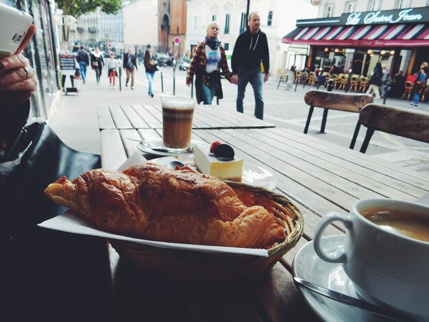 Zbliżenie świeżego croissant i kawy podawanej na stole w kawiarni na chodniku