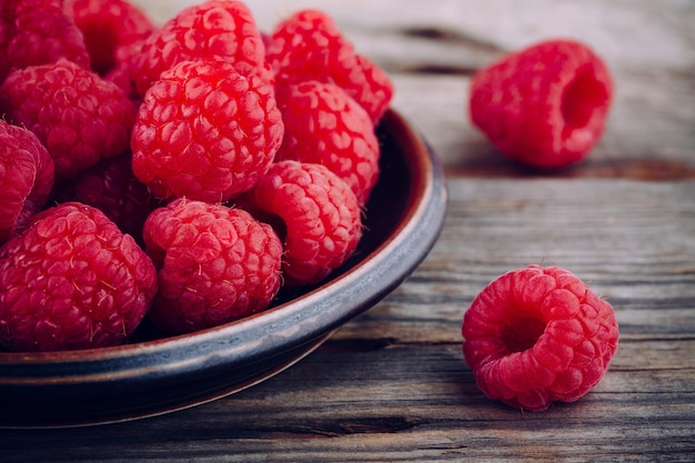 Zbliżenie świeżych dojrzałych organicznych malin na drewnianym tle