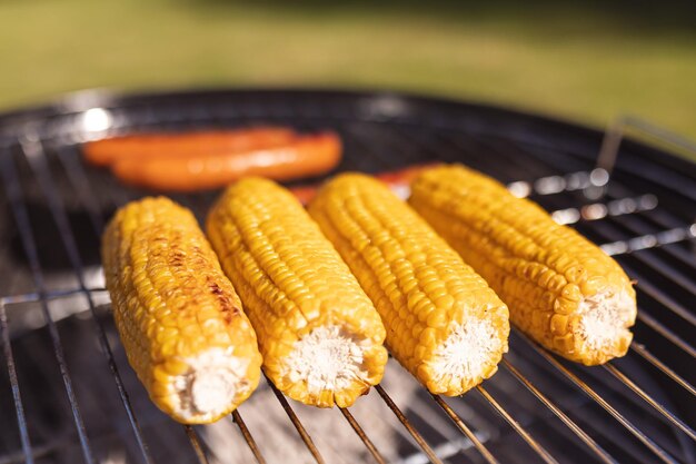 Zbliżenie świeżych kukurydzy z grilla i smacznych kiełbasek na grillu. Latem spędzać czas i relaksować się na świeżym powietrzu.