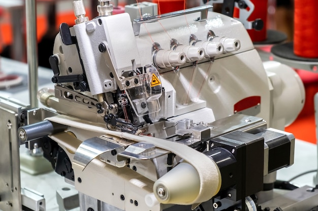 Zbliżenie szczegółów nowoczesnej białej profesjonalnej elektrycznej maszyny do szycia na stole w fabryce.