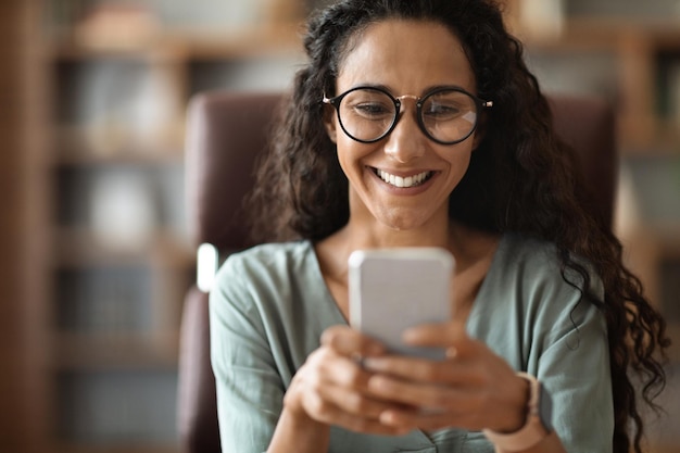 Zbliżenie szczęśliwej brunetki za pomocą smartfona