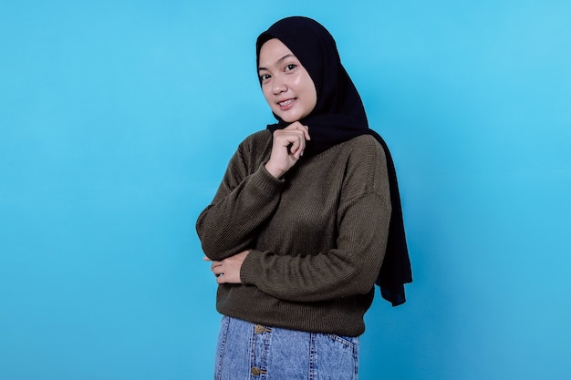 Zbliżenie szczęśliwej dziewczyny noszącej hidżab w swobodnym ubraniu i uśmiechającej się na niebieskiej ścianie