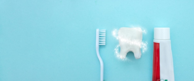Zbliżenie szczoteczki do zębów i pasty do zębów z białym modelem zęba trzonowego i wirem ochronnym