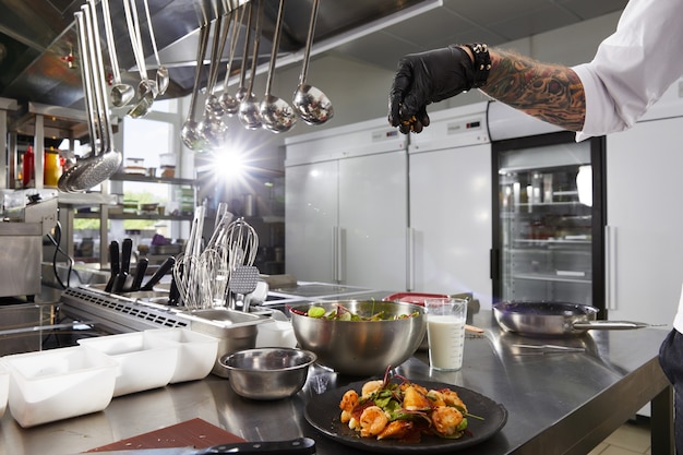 Zdjęcie zbliżenie szefa kuchni przygotowuje sałatkę z krewetek w luksusowej kuchni restauracji