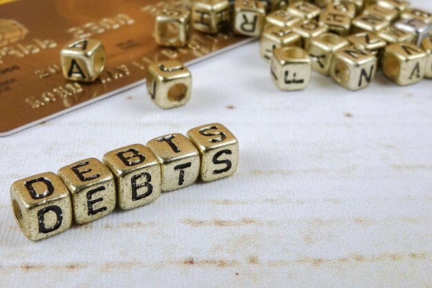 Zdjęcie zbliżenie tekstu długu wykonanego ze złotych bloków zabawek na stole