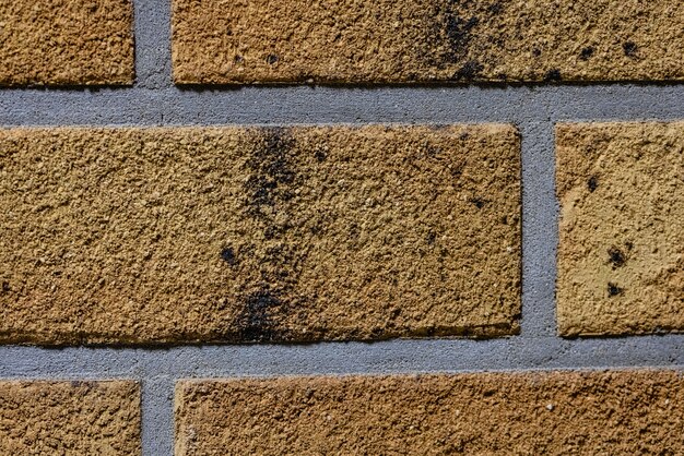 Zbliżenie tekstury żółtej porysowanej ściany z cegły z szarym szwem