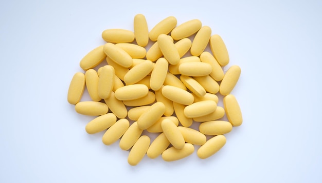 Zbliżenie tekstury żółtych tabletek multiwitaminowych na białym tle Koncepcja zdrowego stylu życia