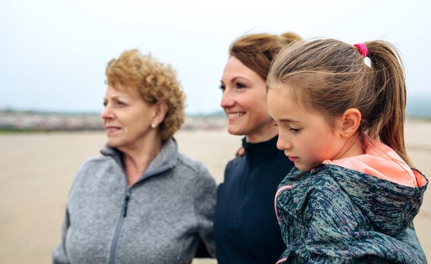 Zbliżenie trzech pokoleń kobiet patrzących na morze na plaży jesienią