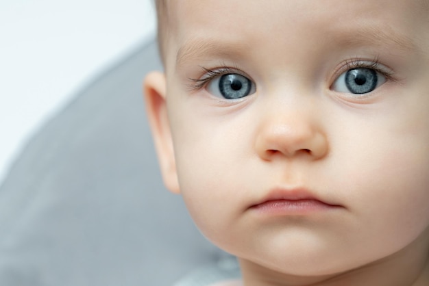 Zbliżenie twarzy dziecka z niebieskimi oczami patrzącym na kamerę
