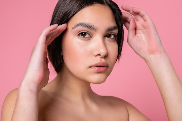 Zbliżenie twarzy pięknej młodej kobiety z czystą idealną skórą Portret modelki urody z naturalnym makijażem nago Spa skóry i odnowy biologicznej Różowy brzoskwiniowy koral tło 169 panoramiczny format