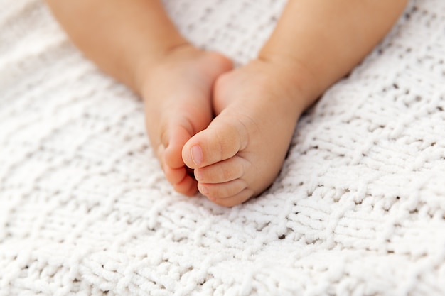 Zbliżenie uroczego dziecka cieki na trykotowym koc jako tło w selekcyjnej ostrości, niemowlak nogi przy naturalnym światłem