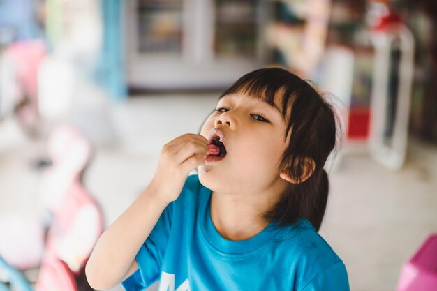 Zbliżenie uroczej dziewczyny jedzącej lody w sklepie.