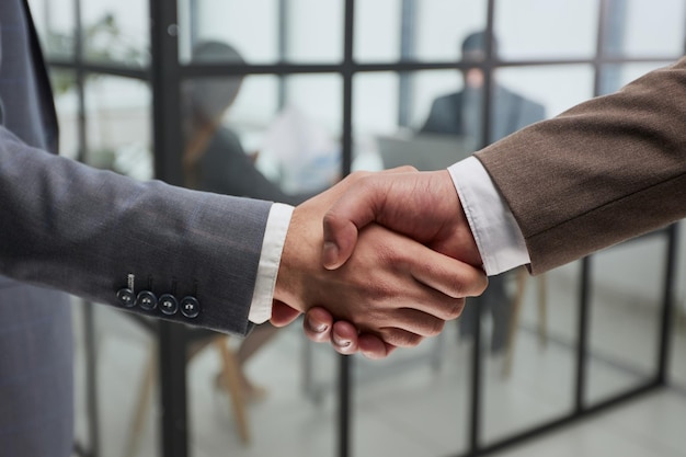 Zbliżenie uścisk dłoni partnerów biznesowych na tle kolegów