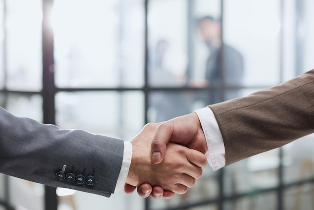 Zbliżenie uścisk dłoni partnerów biznesowych na tle kolegów