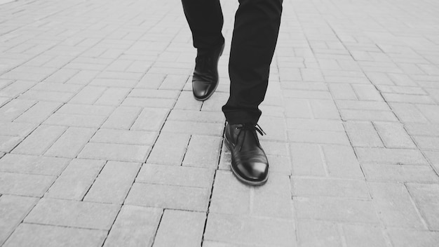 Zbliżenie widok biznesmena w butach chodzenie przed chodnikiem na ulicy