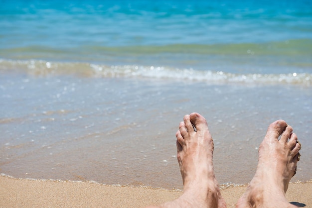 Zbliżenie widok bosych ludzkich stóp na tle piaszczystej plaży. Koncepcja wakacji letnich