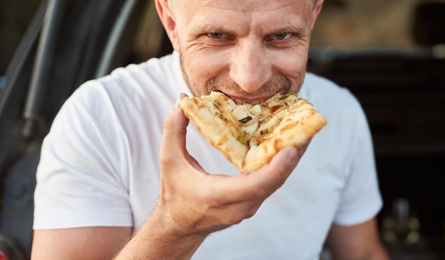 Zbliżenie widok szczęśliwego człowieka jedzącego pizzę