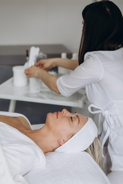 Zdjęcie zbliżenie widok z boku relaks piękna młoda azjatycka kobieta lubi relaksować się podczas peelingu twarzy maska do pielęgnacji skóry zabiegi kosmetyczne spa przez kosmetyczkę w centrum salonu spa zdjęcie wysokiej jakości