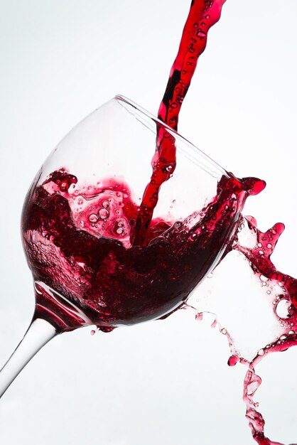 Zdjęcie zbliżenie wina nalewanego do szklanki na białym tle
