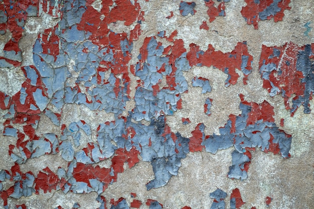 Zbliżenie wyblakły ściany z rozdrobnioną niebieską i czerwoną farbą. Stary kolorowy betonowy mur. pęknięta tekstura