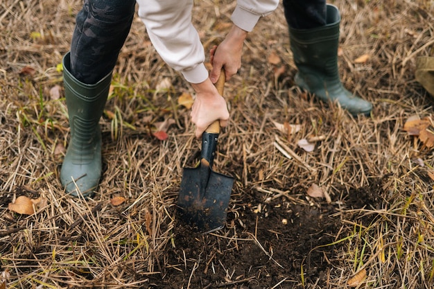 Zbliżenie Wysoki Kąt Widzenia Człowieka Nie Do Poznania, Kopanie Miejsca Na Ognisko Za Pomocą Małej łopaty Na Zewnątrz W Deszczowy Zimny Dzień. Koncepcja Bushcraftu, Campingu I Survivalu W Naturze.