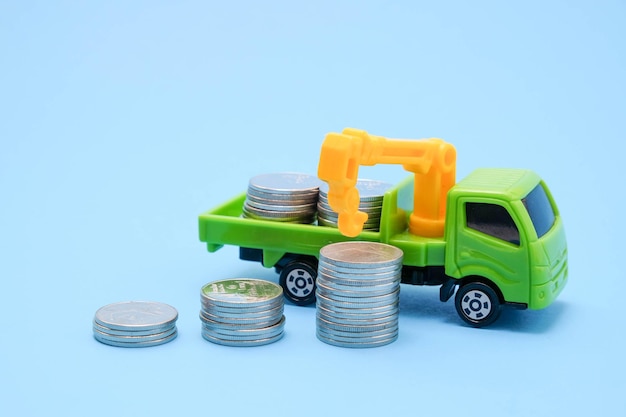 Zdjęcie zbliżenie zabawkowej ciężarówki poprzez układanie monet na niebieskim tle