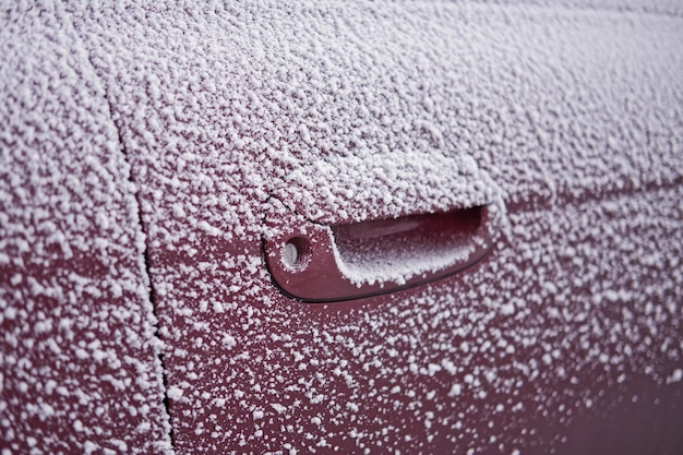 Zbliżenie zamrożonego uchwytu samochodowego pokrytego śniegiem w sezonie zimowym Zimowa koncepcja jazdy samochodem