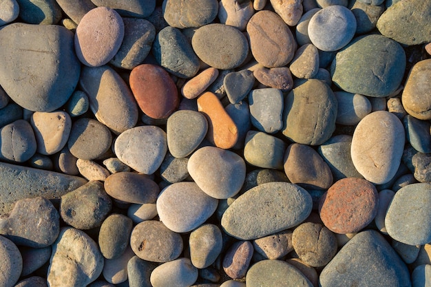 Zbliżenie zaokrąglonych i wypolerowanych skał plażowych Tekstura